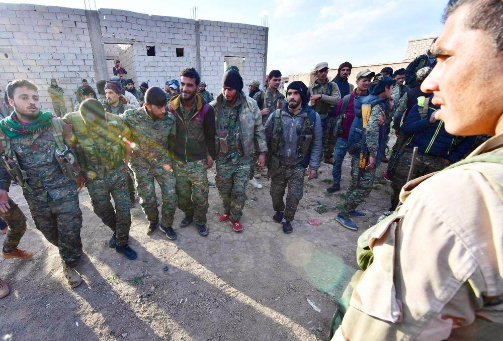 Fighters from the Syrian Democratic Forces (SDF) celebrate as they come back from the frontline in the Islamic State group's last remaining position in the village of Baghouz in the countryside of the eastern Syrian province of Deir Ezzor on March 19, 2019. The Kurdish-led SDF have been closing in on IS fighters holed up in a small sliver of territory in the village of Baghouz in eastern Syria since January.
 / AFP / GIUSEPPE CACACE
