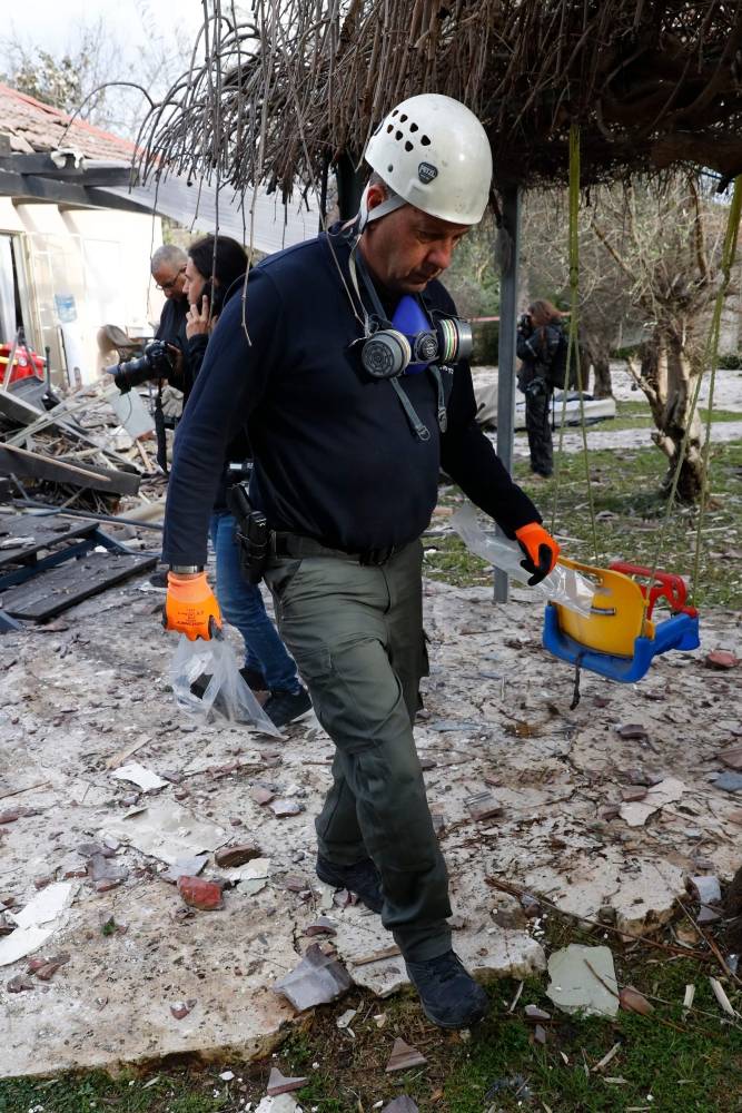 A general view shows emergency responders inspecting a damaged house after it was hit by a rocket in the village of Mishmeret, north of Tel Aviv on March 25, 2019. A rocket hit a house in a community north of Tel Aviv and caused it to catch fire on Monday, wounding five Israelis, police and medics said. / AFP / Jack GUEZ
