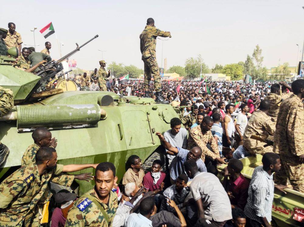 



جنود سودانيون يقفون حول المركبات العسكرية المدرعة، فيما يواصل المتظاهرون احتجاجاتهم بالقرب من مقر الجيش في العاصمة السودانية الخرطوم، أمس. (أ.ف.ب)