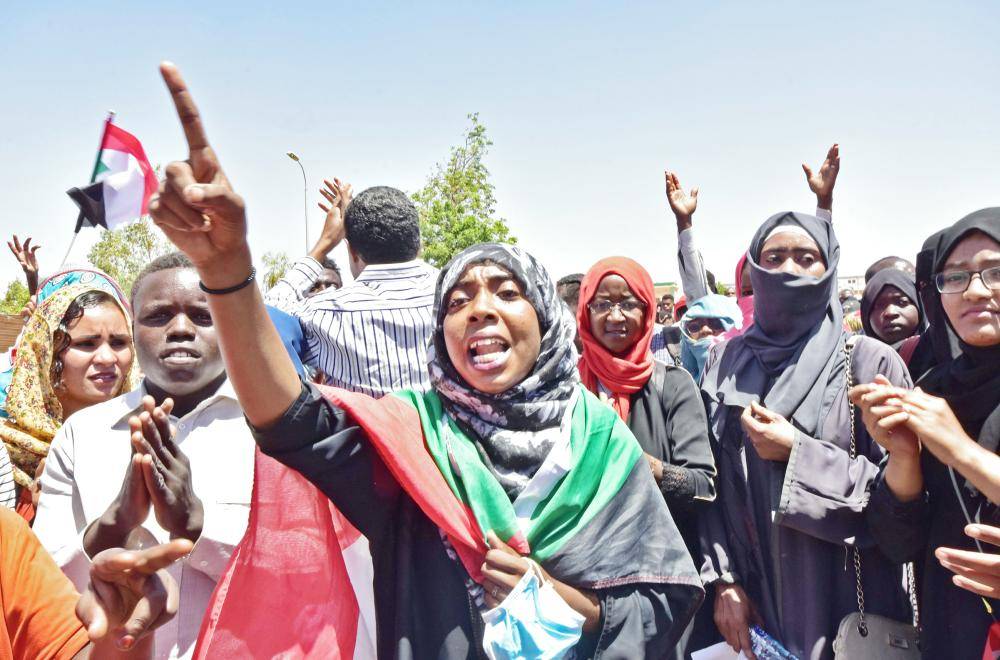 سودانية تلتحف بعلم بلادها وتهتف بشعارات رافضة لفضّ الاعتصام أمام مقر القيادة العسكرية في الخرطوم أمس. (أ.ف.ب)