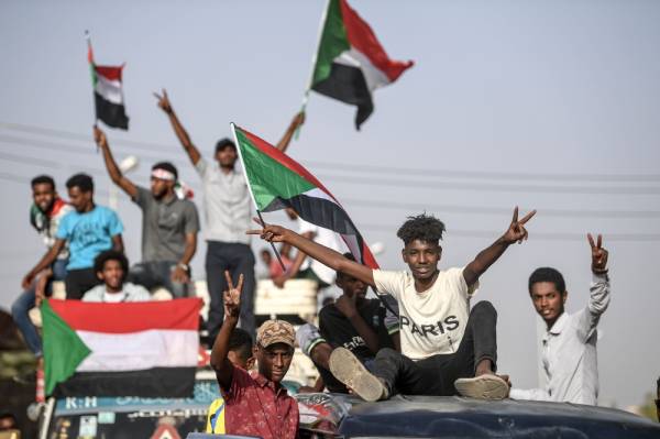 TOPSHOT - Sudanese protesters from the city of Kassala, sitting atop a bus, arrive to join the sit-in outside the army headquarters in the capital Khartoum on April 27, 2019. A joint committee representing Sudan's military leadership and protesters is to hold its first meeting today to discuss their demand for civilian rule, the leading protest group said. / AFP / OZAN KOSE 