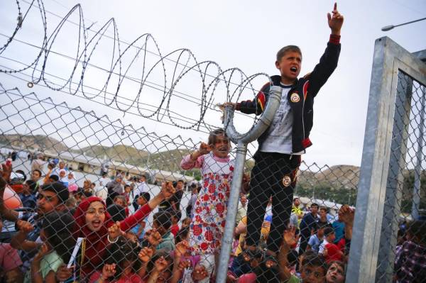 Refugee youths gesture from behind a fence as German Chancellor Angela Merkel, Turkish Prime Minister Ahmet Davutoglu, EU Council President Donald Tusk and European Commission Vice-President Frans Timmermans (all not pictured) arrive at Nizip refugee camp near Gaziantep, Turkey, April 23, 2016. REUTERS/Umit Bektas - RTX2BCD3