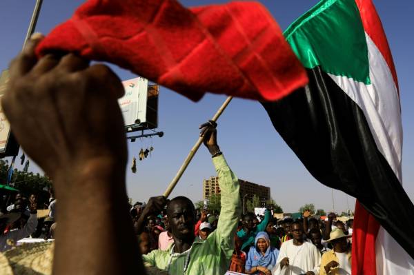 Sudanese protesters march as a man waves a national flag during a demonstration in front of the defense ministry compound in Khartoum, Sudan, May 3, 2019. REUTERS/Umit Bektas