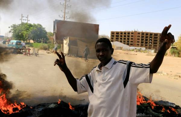 



متظاهر سوداني يرفع علامة النصر أمام إطارات محترقة في طريق يربط الخرطوم بحري والخرطوم. (رويترز)