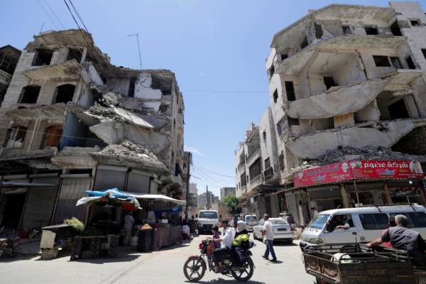 A man rides on a motorbike with his family past damaged buildings in the city of Idlib, Syria May 25, 2019. REUTERS/Khalil Ashawi