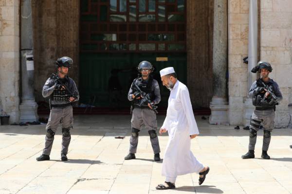 A Palestinian man walks past Israeli policemen as they stand guard during clashes with Palestinians on «Jerusalem Day» on the compound known to Muslims as Noble Sanctuary and to Jews as Temple Mount, in Jerusalem's Old City June 2, 2019. REUTERS/Ammar Awad