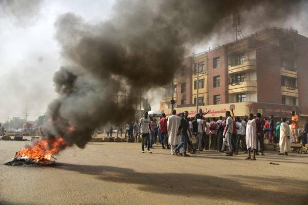 Sudanese protesters walk past burning tyres during a demonstration in Khartoum's twin city of Omdurman on June 3, 2019. At least five protesters were shot dead Monday as Sudan's military rulers tried to break up a sit-in outside Khartoum's army headquarters, a doctors' committee said as gunfire was heard from the site. / AFP / Ahmed Mustafa                       
