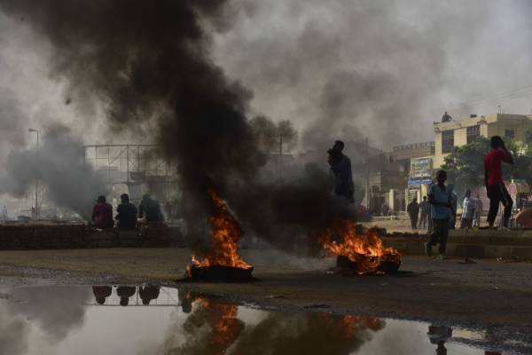 Sudanese protesters walk past burning tyres during a demonstration in Khartoum's twin city of Omdurman on June 3, 2019. At least five protesters were shot dead Monday as Sudan's military rulers tried to break up a sit-in outside Khartoum's army headquarters, a doctors' committee said as gunfire was heard from the site. / AFP / Ahmed Mustafa                       
