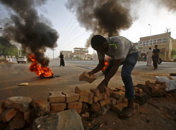 A Sudanese protester uses paving stones to block Street 60 as the military forces tried to disperse the sit-in outside Khartoum's army headquarters on June 3, 2019. At least two people were killed Monday as Sudan's military council tried to break up a sit-in outside Khartoum's army headquarters, a doctors' committee said as gunfire was heard from the protest site.
 / AFP / ASHRAF SHAZLY
