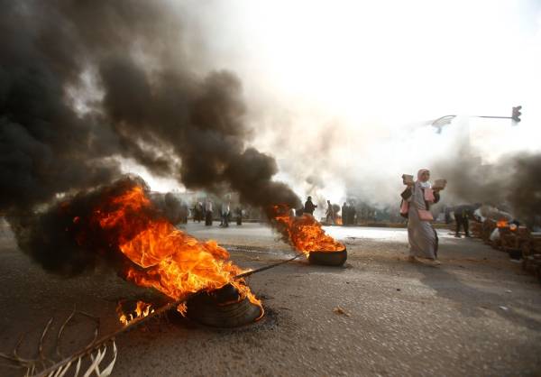 A Sudanese protester walks past burning tyres as Sudan's military forces tried to disperse the sit-in outside Khartoum's army headquarters on June 3, 2019. At least two people were killed Monday as Sudan's military council tried to break up a sit-in outside Khartoum's army headquarters, a doctors' committee said as gunfire was heard from the protest site.
 / AFP / ASHRAF SHAZLY
