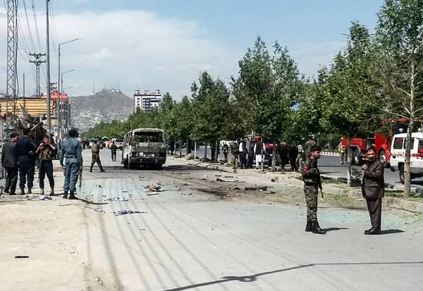 Afghan security personnel stand near a damaged bus carrying a government watchdog agency that was targeted by a bomb blast in Kabul on June 3, 2019, a day after blasts hit a first bus.  At least four people were killed on June 3 when a bomb tore through a bus in Kabul, an official said, marking the second day straight that attackers have targeted a bus. / AFP / STR
