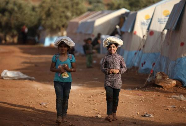 Displaced Syrian girls walk in a camp for internally displaced people camp near Kah, in the northern Idlib province near the border with Turkey on June 3, 2019 on the eve of Eid al-Fitr, which marks the end of the Muslim holy fasting month of Ramadan. The conflict in Syria has killed more than 370,000 people and displaced millions since it started in 2011. / AFP / Aaref WATAD
