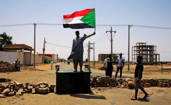 A Sudanese protester holds a national flag as he stands on a barricade along a street, demanding that the country's Transitional Military Council hand over power to civilians, in Khartoum, Sudan June 5, 2019. REUTERS/Stringer     TPX IMAGES OF THE DAY