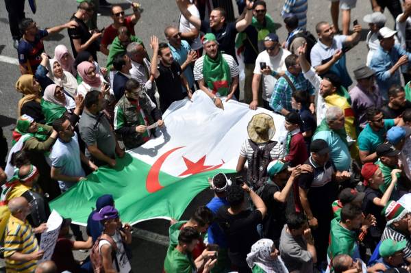 Algerian protesters hold the national flag as they demonstrate in the capital Algiers on June 7, 2019. Interim Algerian president Abdelkader Bensalah on June 6 called for «dialogue» after the authorities ruled out holding a planned election on July 4. / AFP / RYAD KRAMDI 
