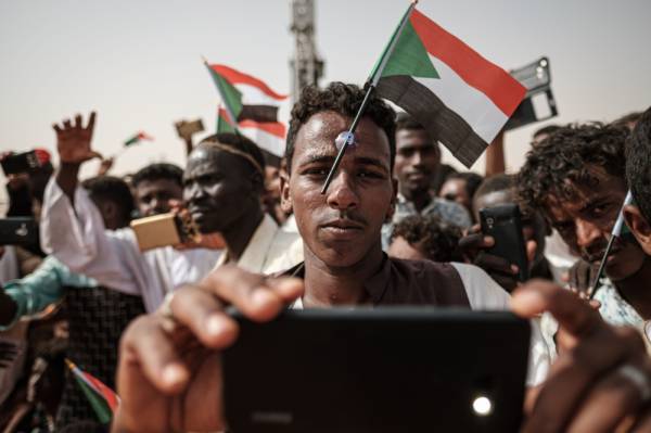 (FILES) In this file photo taken on June 22, 2019 A man poses for a «selfie» photo with a cell phone as he awaits the arrival of the deputy head of Sudan's ruling Transitional Military Council (TMC) and commander of the Rapid Support Forces (RSF) paramilitaries, during a rally in the village of Abraq, about 60 kilometers northwest of Khartoum. / AFP / Yasuyoshi CHIBA 