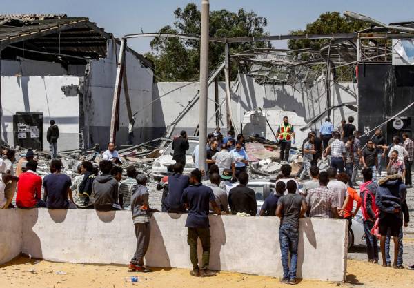 Migrants are seen outside at a detention centre used by the Libyan Government of National Accord (GNA) in the capital Tripoli's southern suburb of Tajoura on July 3, 2019, following an air strike on a nearby building that left dozens killed the previous night. Over 40 migrants were killed in an air strike early late on July 2 on their detention centre in a Tripoli suburb blamed on Libyan strongman Khalifa Haftar, who has been trying for three months to seize the capital. The UN said the air strike 