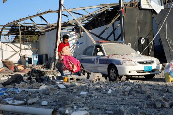 FILE PHOTO: A migrant picks up clothes from among rubble at a detention centre for mainly African migrants that was hit by an air strike in the Tajoura suburb of the Libyan capital of Tripoli, July 3, 2019. REUTERS/Ismail Zitouny/File Photo