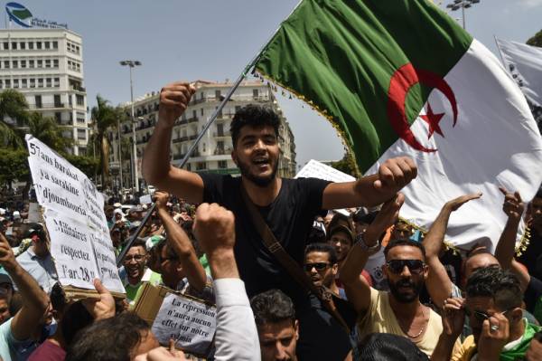 Algerian demonstrators wave a national flag and carry placards staing their demands as they take part in a protest in the streets of the capital Algiers on July 9, 2019. Hundreds of Algerian students and teachers demonstrated today for the 20th consecutive week, demanding a «regime change» and the release of «political detainees,» said an AFP journalist.
/ AFP / RYAD KRAMDI 