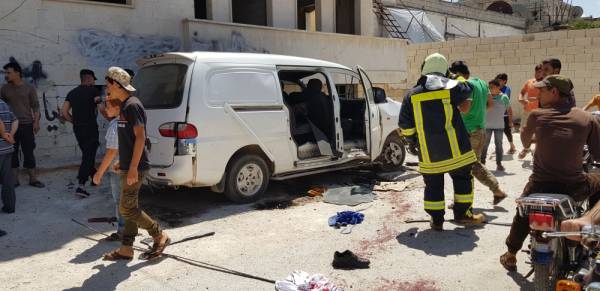 Onlookers gather at the site of a reported car bomb attack outside a police station in Binnish in Syria's northern Idlib province, on July 19, 2019. / AFP / Muhammad HAJ KADOUR
