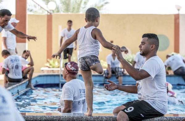 A trainer helps a Palestinian amputee child during a summer camp origanized by the Palestinian Children's Relief Fund (PCRF) in the town of Khan Yunis in the southern Gaza strip on August 3, 2019. PCRF is a non-governmental organisation providing physical and psychological services for disabled children in Gaza Strip. The organisation has launched its first summer camp this year targeting children who lost their limbs during the Israeli wars. / AFP / SAID KHATIB
