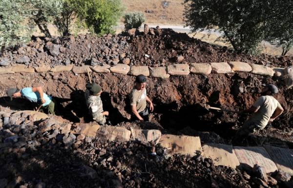 FILE PHOTO: Volunteers use shovels to dig a trench in the town of Salqin, Syria, June 23, 2019. Picture taken June 23, 2019. REUTERS/Khalil Ashawi/File Photo