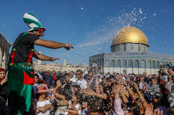 TOPSHOT - A clown entertains Palestinians on the first day of Eid al-Adha near the Dome of Rock mosque at the Al-Aqsa Mosque compound, Islam's third most holy site, in the Old City of Jerusalem on august 11, 2019. Muslims across the world are celebrating the first day of the Feast of Sacrifice, which marks the end of the hajj pilgrimage to Mecca and commemorates prophet Abraham's sacrifice of a lamb after God spared Ishmael, his son. / AFP / Ahmad GHARABLI
