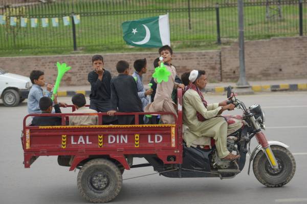 CORRECTION / Youths gesture on a modified three wheel vehicle during Independence Day celebrations in Peshawar on August 14, 2019, as the nation marks the 73rd anniversary of independence from British rule. / AFP / ABDUL MAJEED 