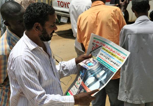 A Sudanese man reads the newspaper on August 20, 2019 headlining the court appearance of Sudan's deposed military ruler Omar al-Bashir during the opening of his corruption trial the previous day. / AFP / Ebrahim HAMID
