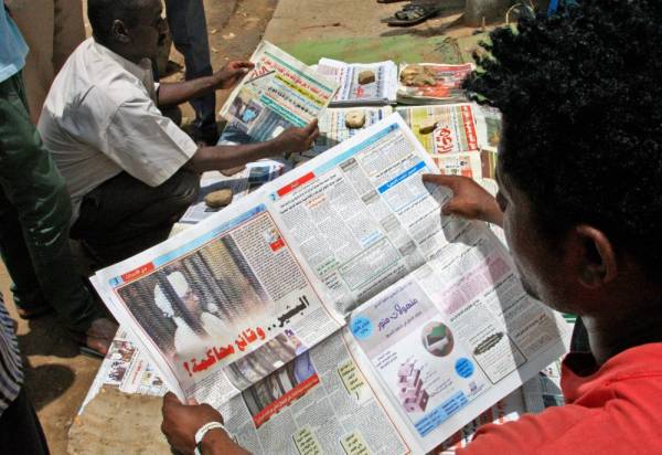 A Sudanese man reads the newspaper on August 20, 2019 headlining the court appearance of Sudan's deposed military ruler Omar al-Bashir during the opening of his corruption trial the previous day. / AFP / Ebrahim HAMID
