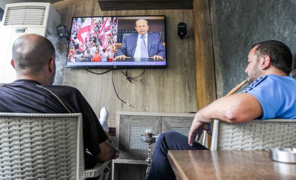 Lebanese men smoke waterpipe (shisha or hookah) as they watch a televised speech by President Michel Aoun, at a cafe in the capital Beirut on October 24, 2019, as Aoun addresses demonstrators on the eighth day of protests against tax increases and official corruption. The Lebanese president broke his silence after a week of unprecedented protests and expressed willingness to meet the demonstrators. / AFP / IBRAHIM AMRO
