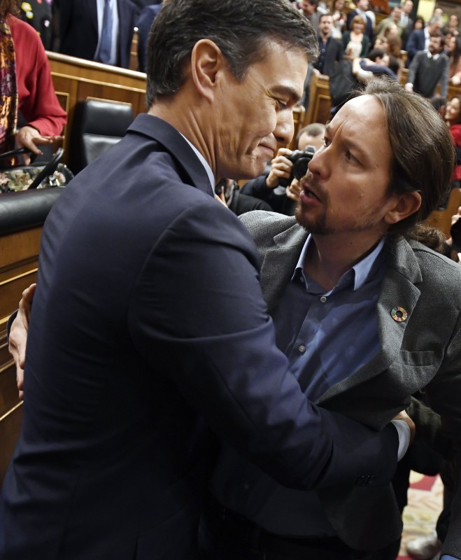 Spanish caretaker prime minister, socialist Pedro Sanchez, is congratulated by Spanish far-left Unidas Podemos coalition leader, Pablo Iglesias (R), after winning a parliamentary vote to elect a premier at the Spanish Congress (Las Cortes) in Madrid on January 7, 2020. Spain's parliament today confirmed Socialist leader Pedro Sanchez by a razor-thin margin as prime minister for another term at the helm of the country's first-ever coalition government since its return to democracy in the 1970s. Sanchez, who has stayed on as a caretaker premier since inconclusive elections last year, got 167 votes in favour in the 350-seat assembly comapred to 165 against, with 18 abstentions from Catalan and Basque separatist lawmakers. / AFP / PIERRE-PHILIPPE MARCOU
