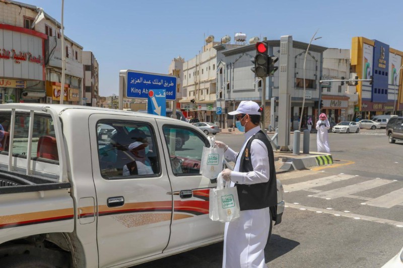 متطوع يوزع المعقمات عند الإشارة الضوئية.