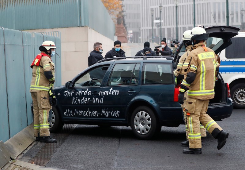 Firefighters remove the car which crashed into the gate of the main entrance of the chancellery in Berlin, the office of German Chancellor Angela Merkel in Berlin, Germany, November 25, 2020. Letters written on the car read: «You damn killers of children and old people». REUTERS/Fabrizio Bensch