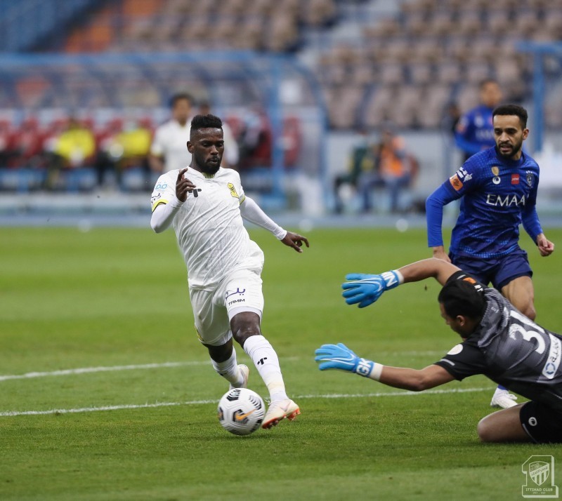 مهاجم الاتحاد عبدالعزيز البيشي في محاولة لتجاوز حارس الهلال حبيب الوطيان. (عكاظ)