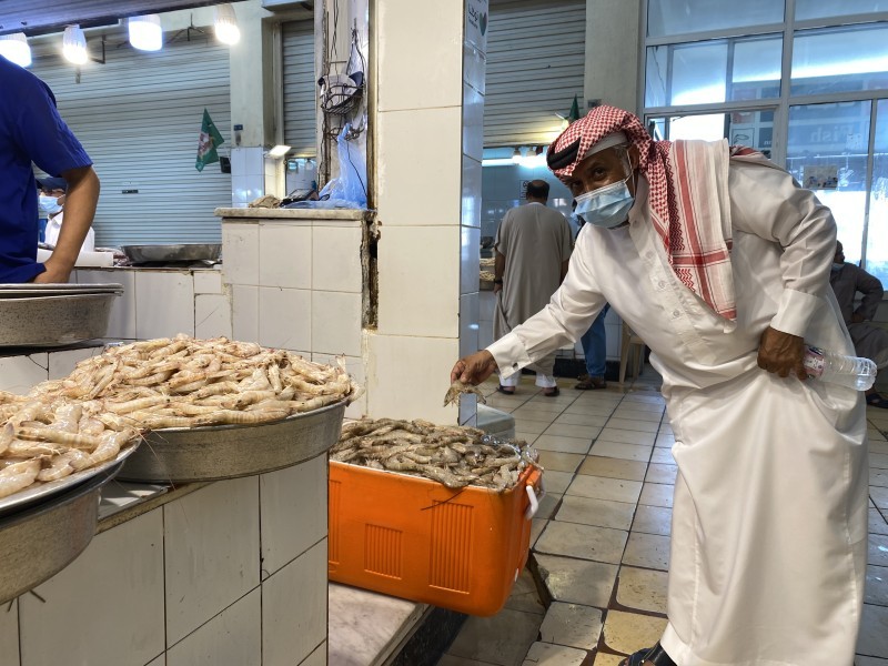 مواطن يتفحص الروبيان قبل شرائه في سوق الدمام المركزي للأسماك أمس. (تصوير: محمد الشهراني)