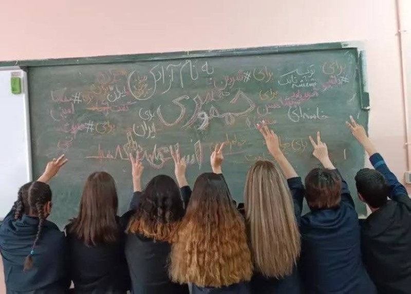 طلاب مدرسة ثانوية في إيران يرفعون علامة النصر ويديرون ظهورهم.
