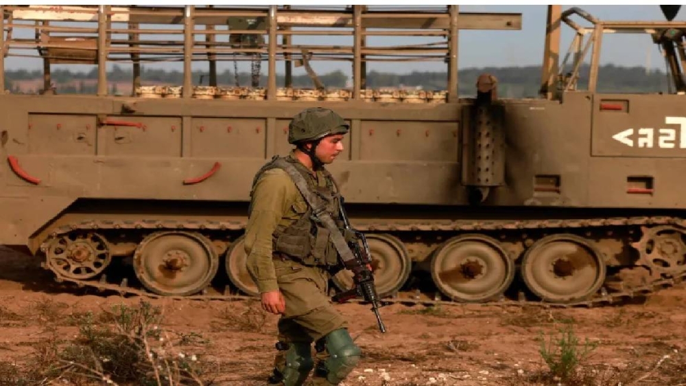 جندي إسرائيلي بجوار آلية عسكرية محترقة .
