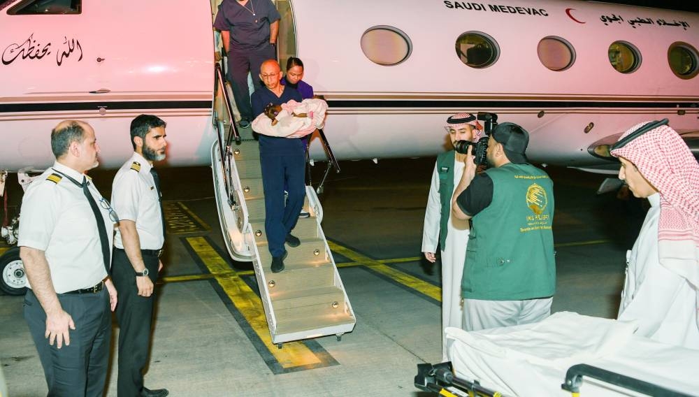 الطاقم الطبي يحمل السيامي النيجيري نزولاً من الطائرة لنقله إلى المستشفى.  (واس)