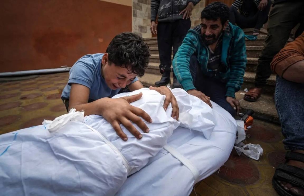 فلسطينيون يبكون مقتل أحد أفراد أسرتهم في العدوان الإسرائيلي على غزة .