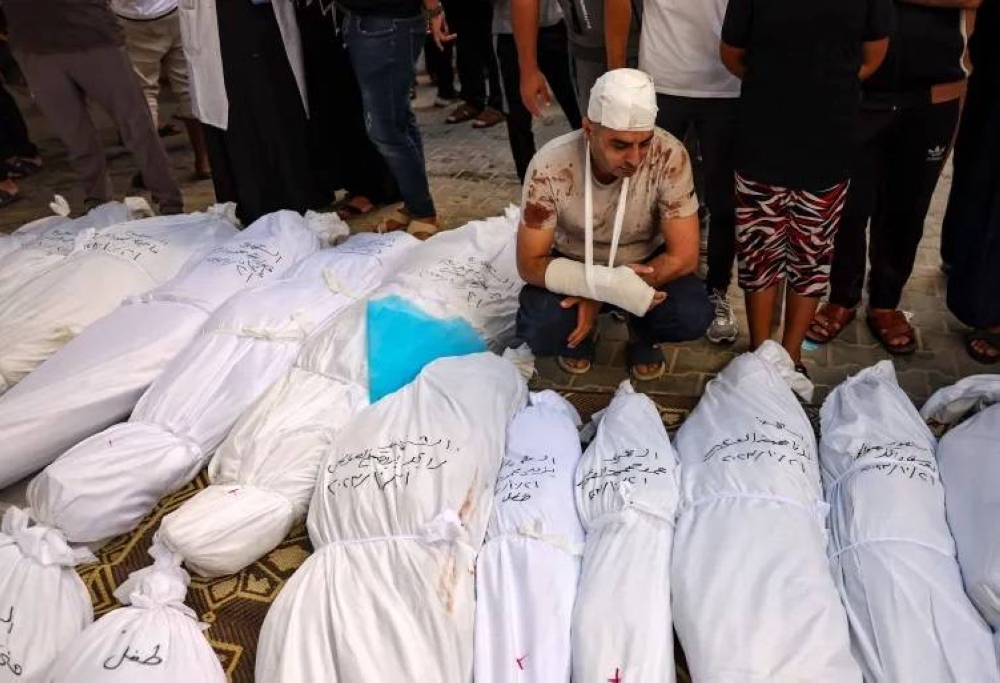 فلسطينيون يقفون على جثث اسرهم الذي أبادهم الإحتلال في غزة