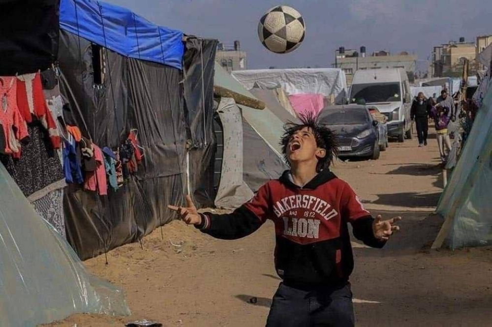 طفل فلسطيني يداعب الكرة  في مركز إيواء بمدينة رفح جنوب قطاع غزة. (وكالات)