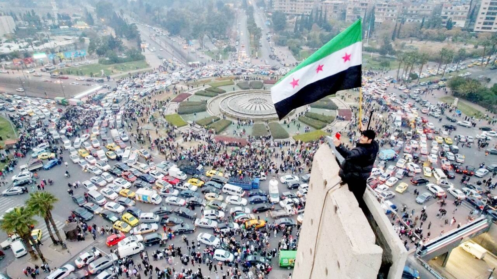 



سوري على أعلى برج في وسط دمشق احتفالاً بسقوط الأسد.